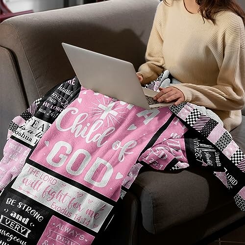 Woman sitting on a couch with a laptop and an inspirational quilt.